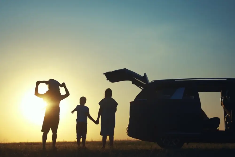 Family enjoying the sunset beside a camping van